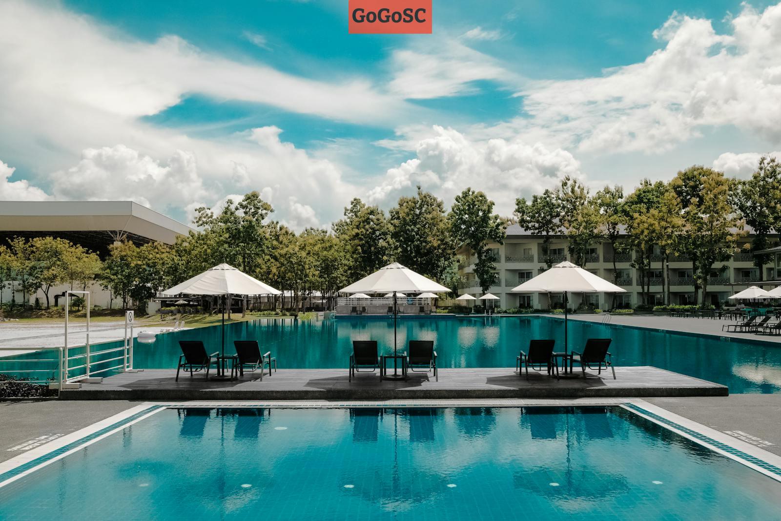 Black Outdoor Lounge Chair in Between Blue Swimming Pool Under White Cloudy Blue Sky